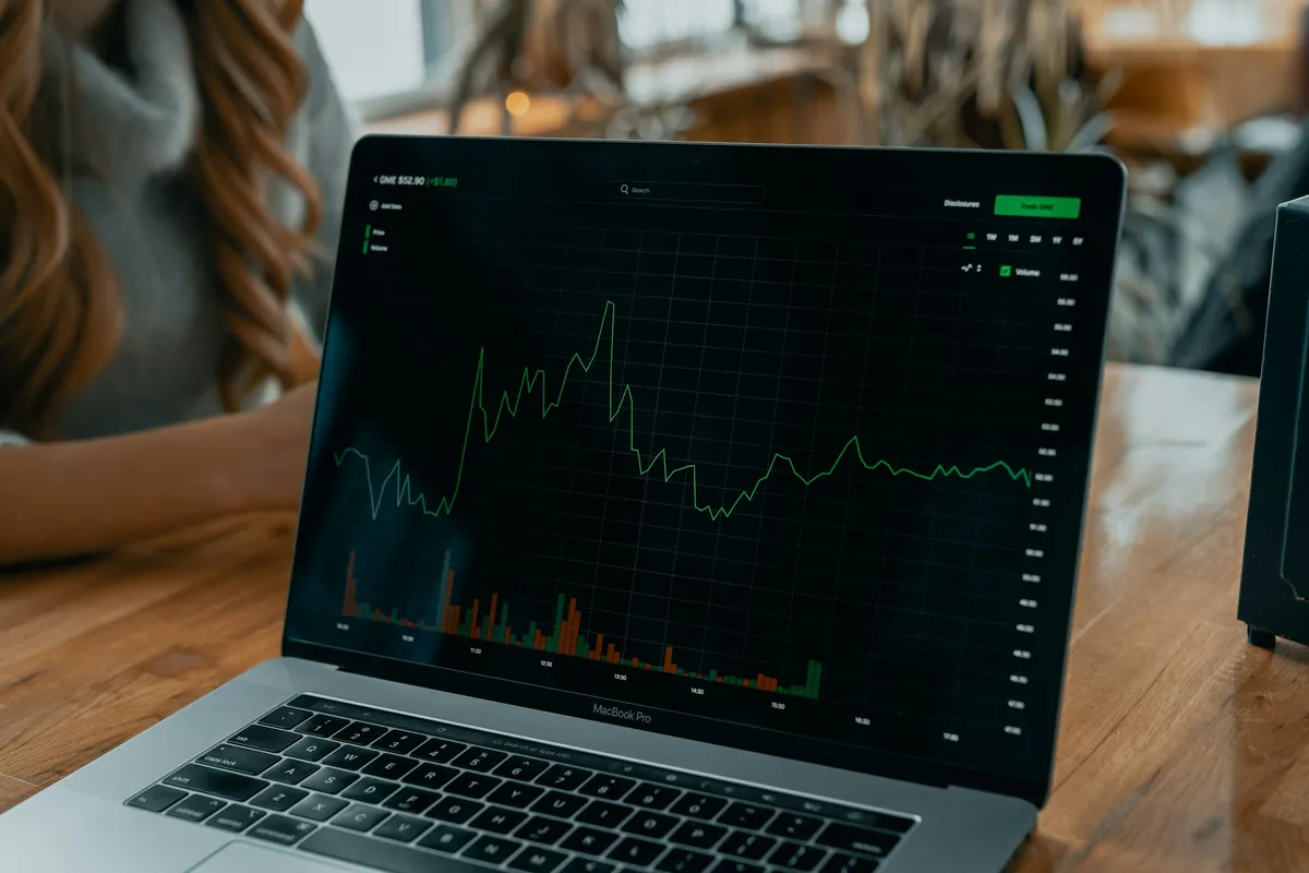 HAULS Journal photo of a laptop on a wooden desk showing a green line chart with volume bars on a dark screen